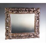 A 19th century painted giltwood mirror, the carved leaf swept frame enclosing a later mirrored