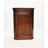 A George III oak and mahogany cross banded flat front hanging corner cupboard, with a moulded