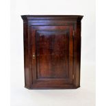 A George III oak flat-front hanging corner cupboard, with a moulded cornice above a single door