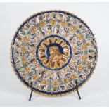 PIATTO in ceramica smaltata e decorata con al centro medaglione raffigurante "Volto di regnante" (