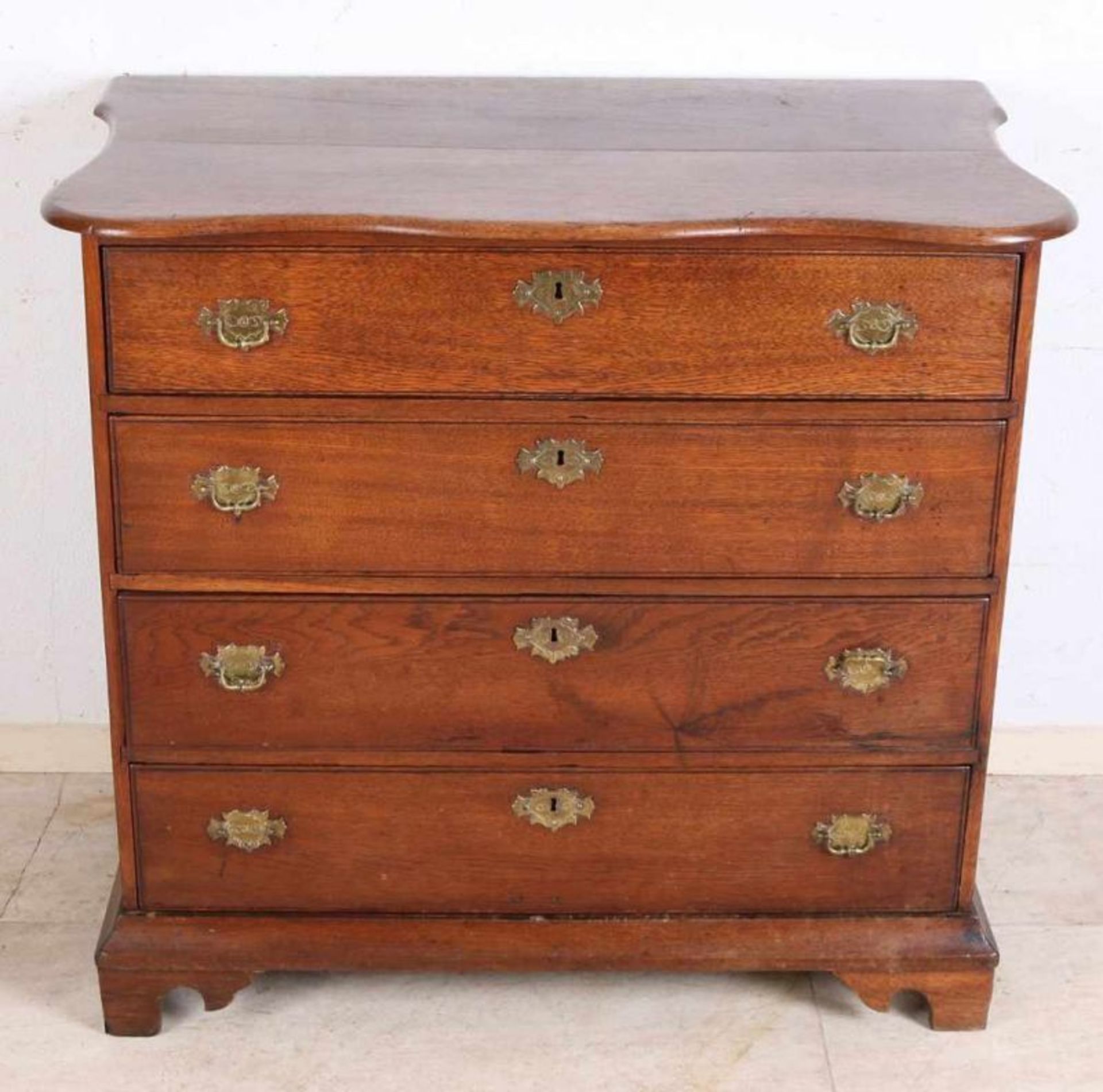 Dutch oak 4-drawer chest of drawers with contoured top and original brass fittings. Around 1800.