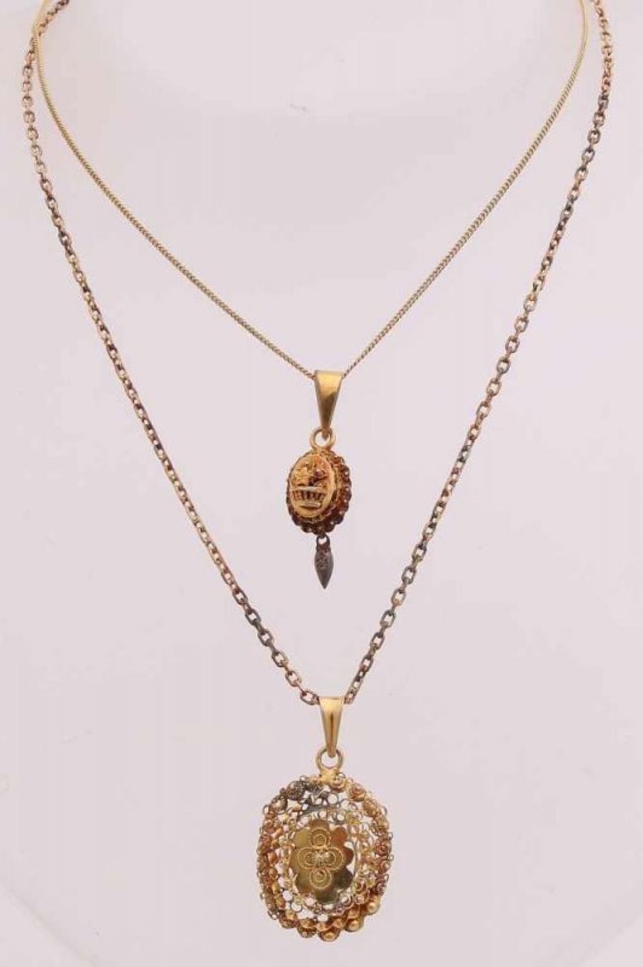 Two yellow gold regional pendants, 585/000, a small oval model with a flower basket with star and