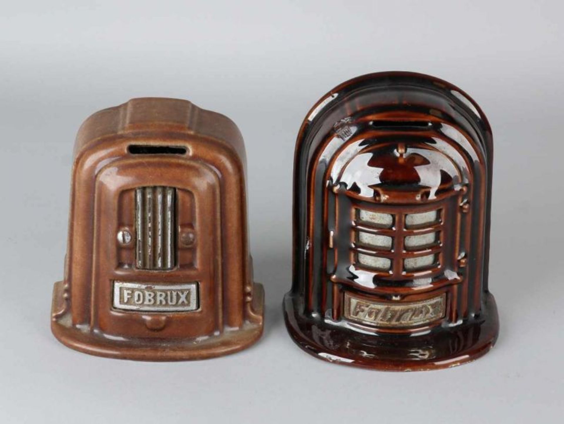 Two antique enameled cast iron money boxes. Fobrux. Circa 1930. One damaged. Dimensions: 14 - 15 cm.