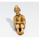 NETSUKE: HOFDIENER. Japan. 19. Jh. Auf der Schleppe seines kariginu-Gewandes sitzend. Elfenbein