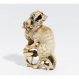 GROßES NETSUKE MIT SHISHI-LÖWE UND HOCKER. Japan. Meiji-Zeit. 19. Jh. Elfenbein, geschnitzt und