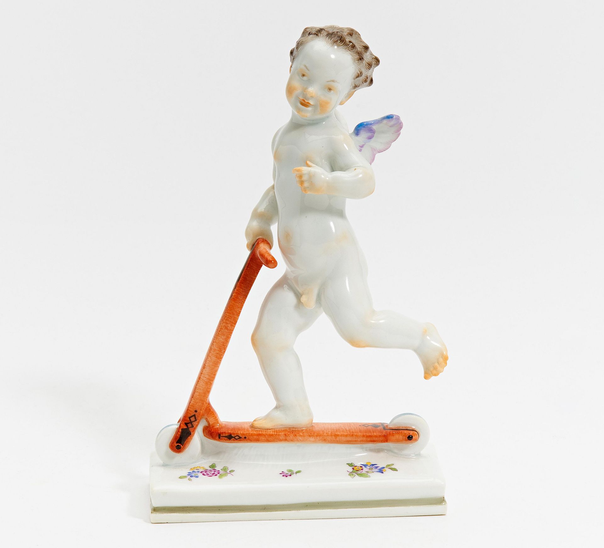 PUTTO AUF ROLLER. Meissen. 1924-1934. Modell L. Nick. Porzellan, farbiges Dekor. Höhe 17,5cm.