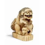 NETSUKE: SHISHI MIT JUNGES AUF SOCKEL. Japan. 19. Jh. Elfenbein. Höhe 5cm. Zustand A/B.