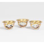 THREE PORCELAIN TEA BOWLS WITH LANDSCAPE CARTOUCHES. Meissen. Um 1725/30. Porzellan, farbig und gold