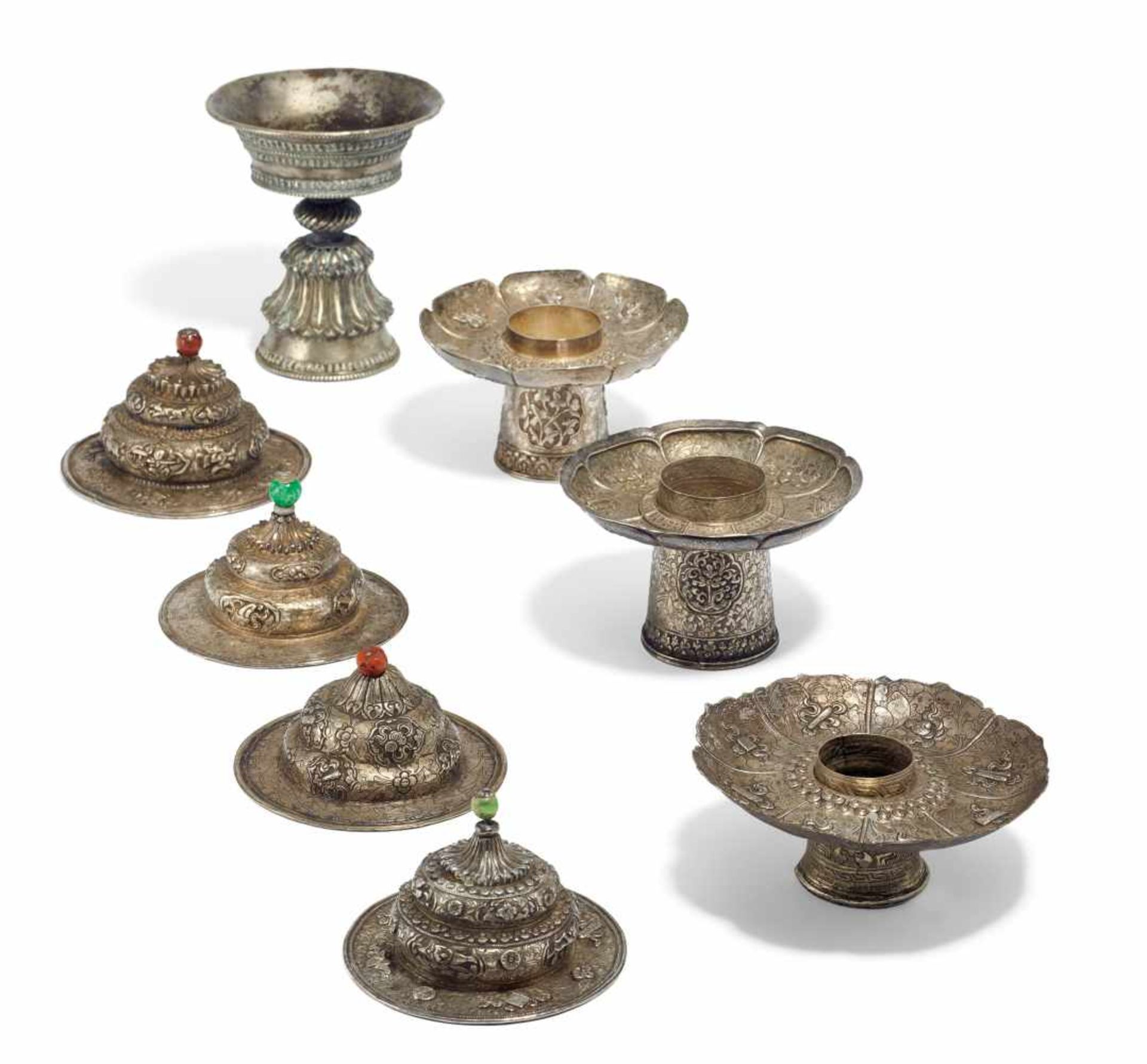 ONE BUTTER LAMP, THREE BASES AND FOUR LIDS FOR TEA BOWLS. Tibet. 19th/20th c. Silver in repoussé.