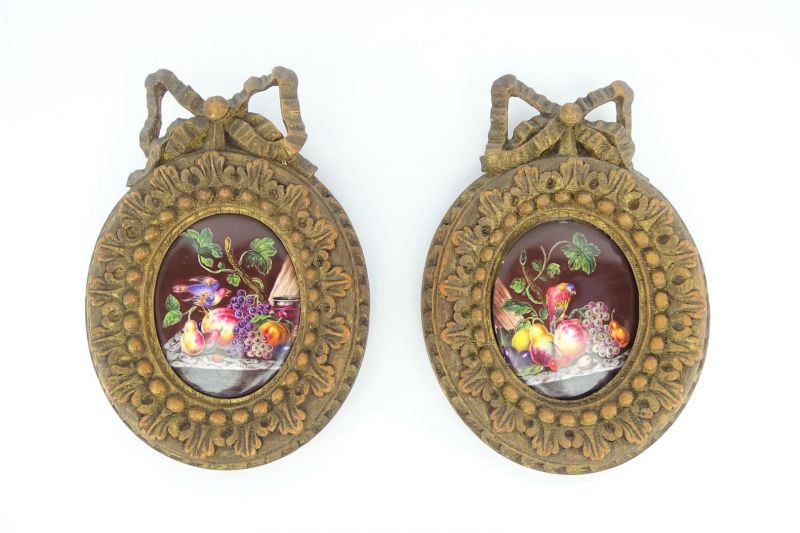 2 ovale emaille plaquettes met voorstelling van bloemstillevens, voorzien van gestoken houten