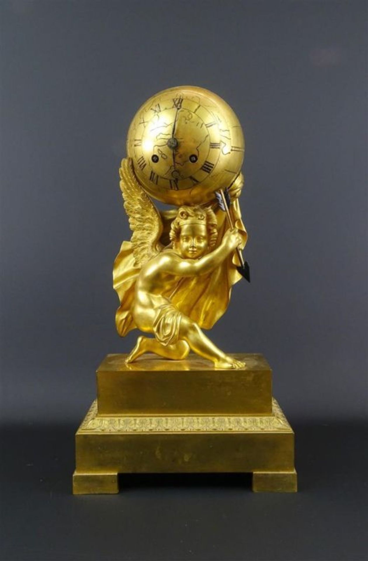 Franse vuurvergulde bronzen empire pendule met voorstelling van globe gedragen door Amor met pijl,