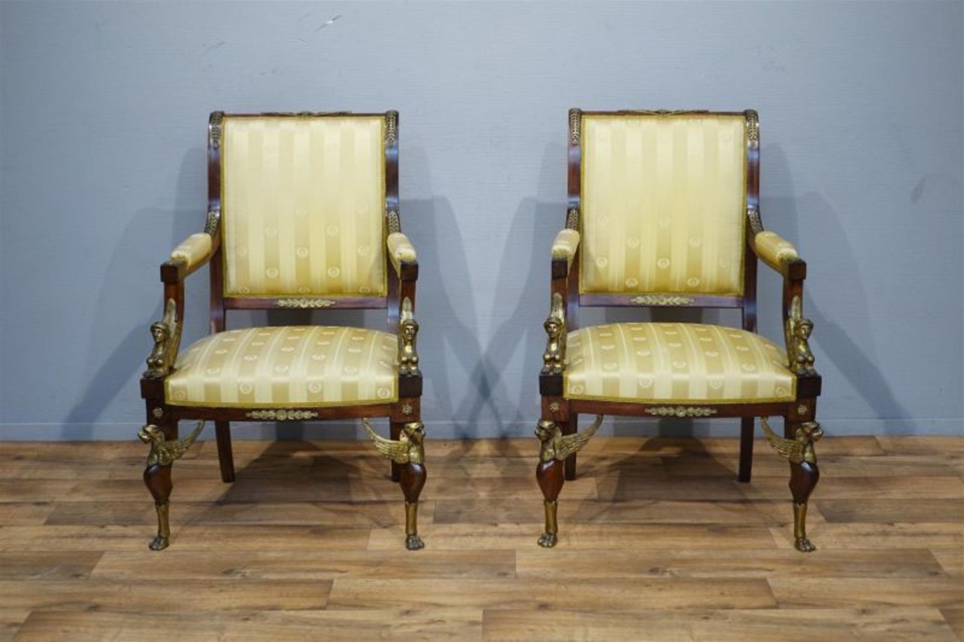 stel mahonie fauteuils met rechte rug, rijkelijk versierd met fleur-de-lis en mascarons, de