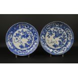 2 blauw/wit Chinees porseleinen borden met decor van bloemen en antiquiteiten, Kangxi, circa 1700,