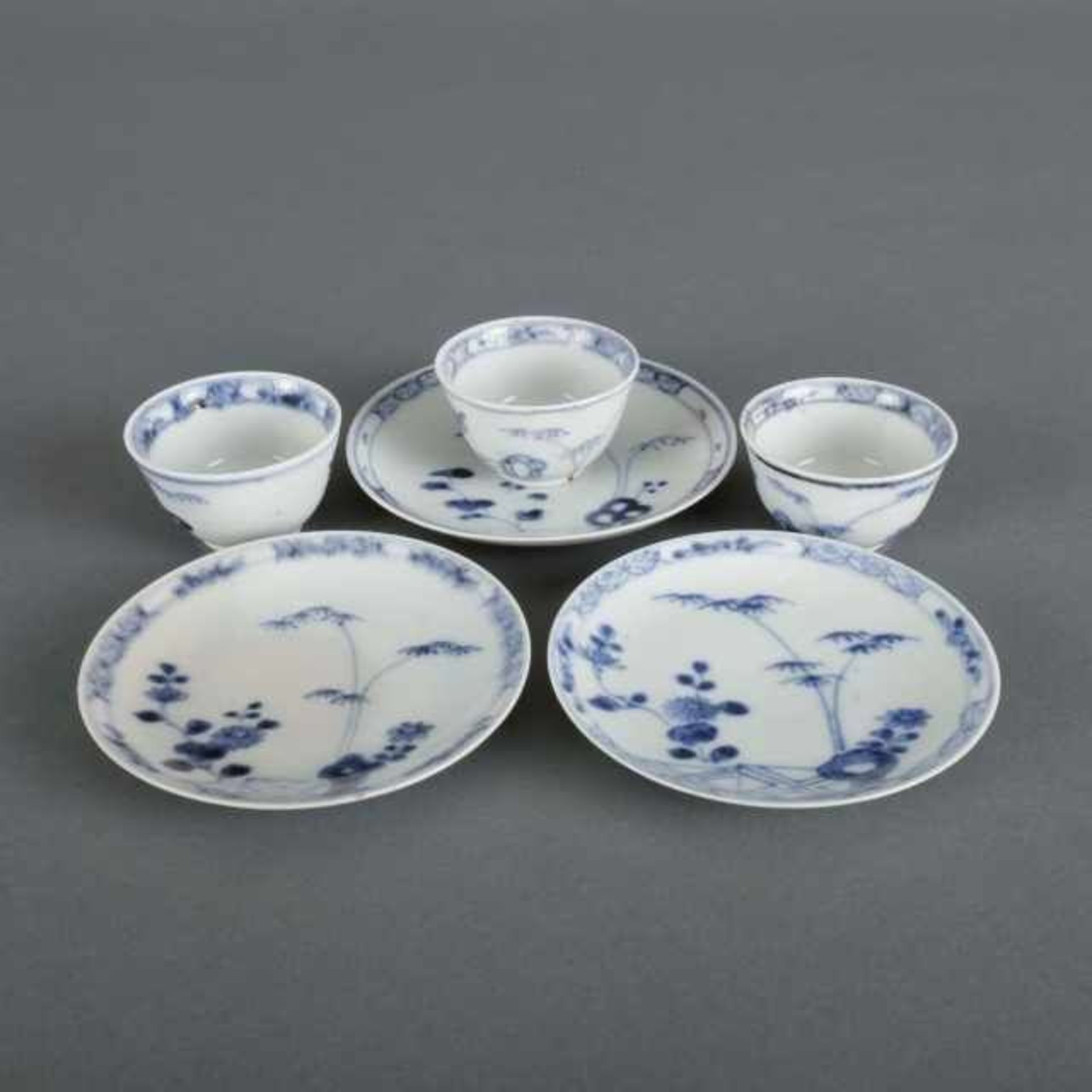 Three miniature blue and white porcelain cups and saucers decorated with a garden motif, after a