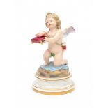 A porcelain figurine, a kneeling Cupid presenting a burning heart on a pillow. Marked in under glaze