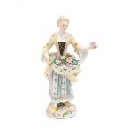 A porcelain figurine, flower girl with a basket of flowers and a rose in her hand. Marked with