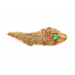 A 14 carat yellow gold brooch of brutalist design. Set with an oval facetted green tsavorite