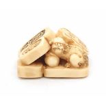 A Japanese ivory netsuke in the shape of three seals and a shishi with ball. Meiji period (1868-