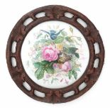 A round porcelain plaque in a carved Schwartzwald frame, decorated with two birds near a nest