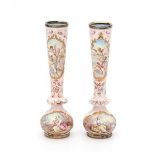 A pair of enamelled miniature vases, decorated with romantic scenes in cartouches on a soft pink