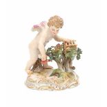 A porcelain figurine, Amor catching flying hearts. Marked with crossed swords and model 'O186'.