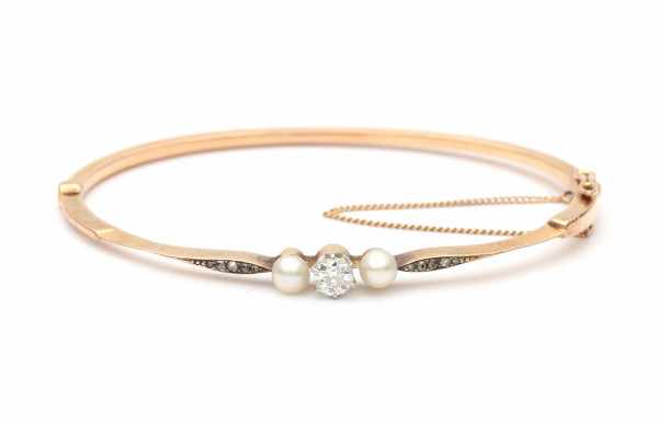 A 14 krt rose gold hinged bracelet. Late 19e - early 20e century. Set with two cultured pearls, an