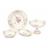 Four pierced porcelain serving dishes, one footed, all decorated with a variety of flowers. Marked