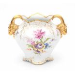 A part gilt porcelain vase, decorated with flowers. The handles in the shape of rams heads. Marked