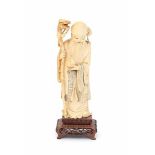 A Chinese ivory sculpture, Shoulao, dressed in long robes, holding a peach and a staff. Circa