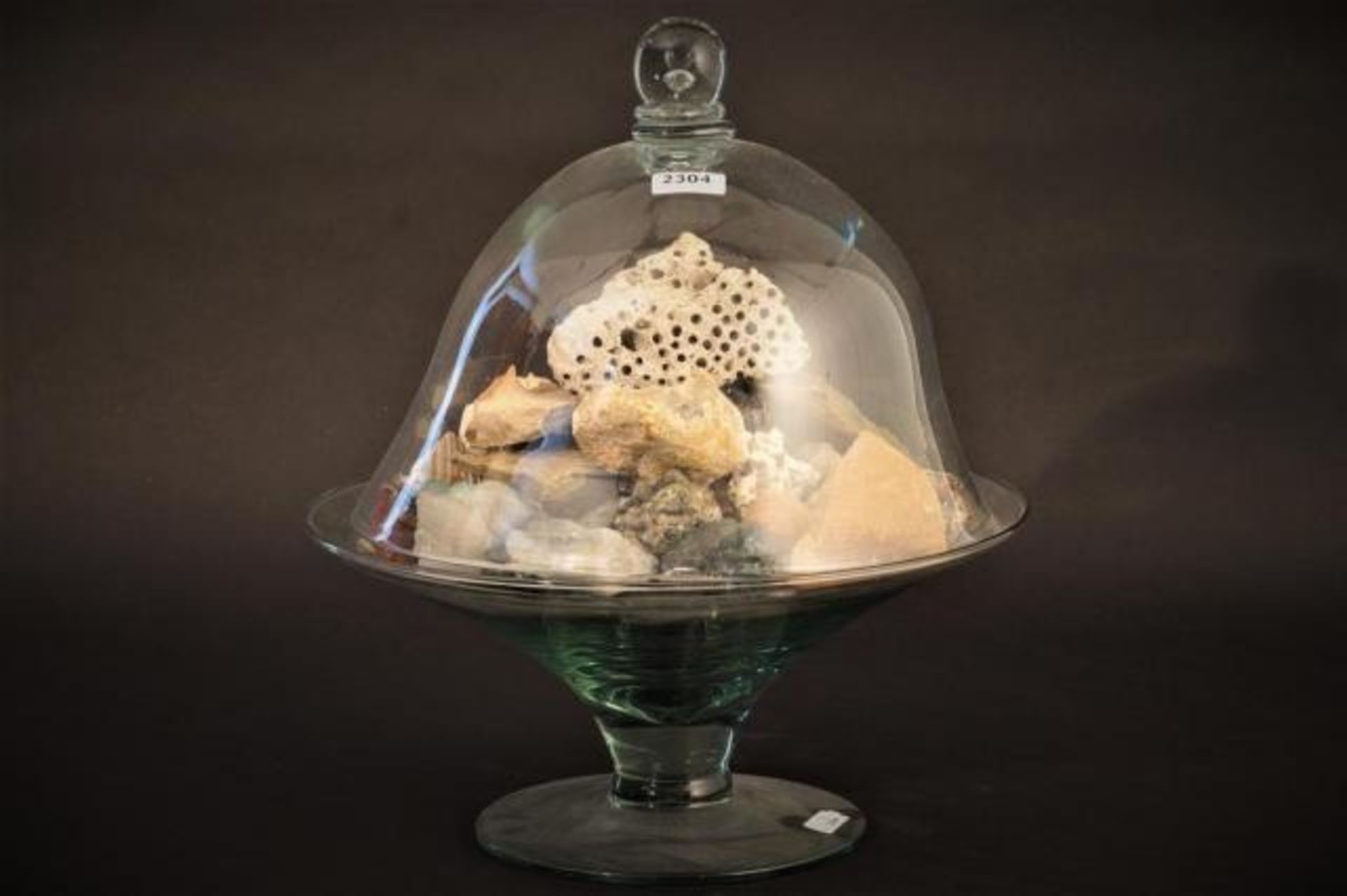 Glass bell jar on glass plateau, filled with stones, h. 38 cm.