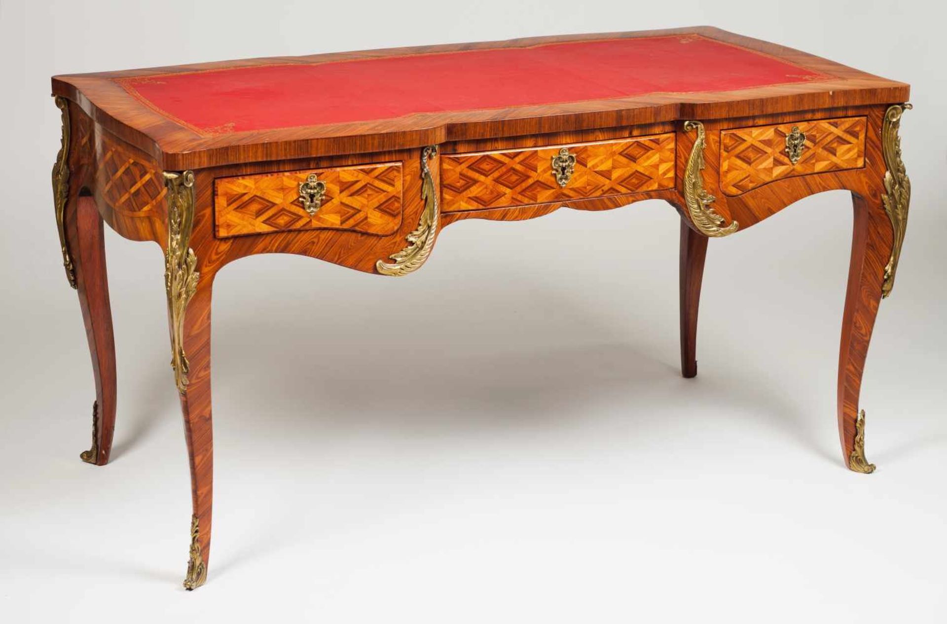 A Louis XV style bureau platRosewood and kingwoodGilt bronze mountsThree drawersRed leather veneered