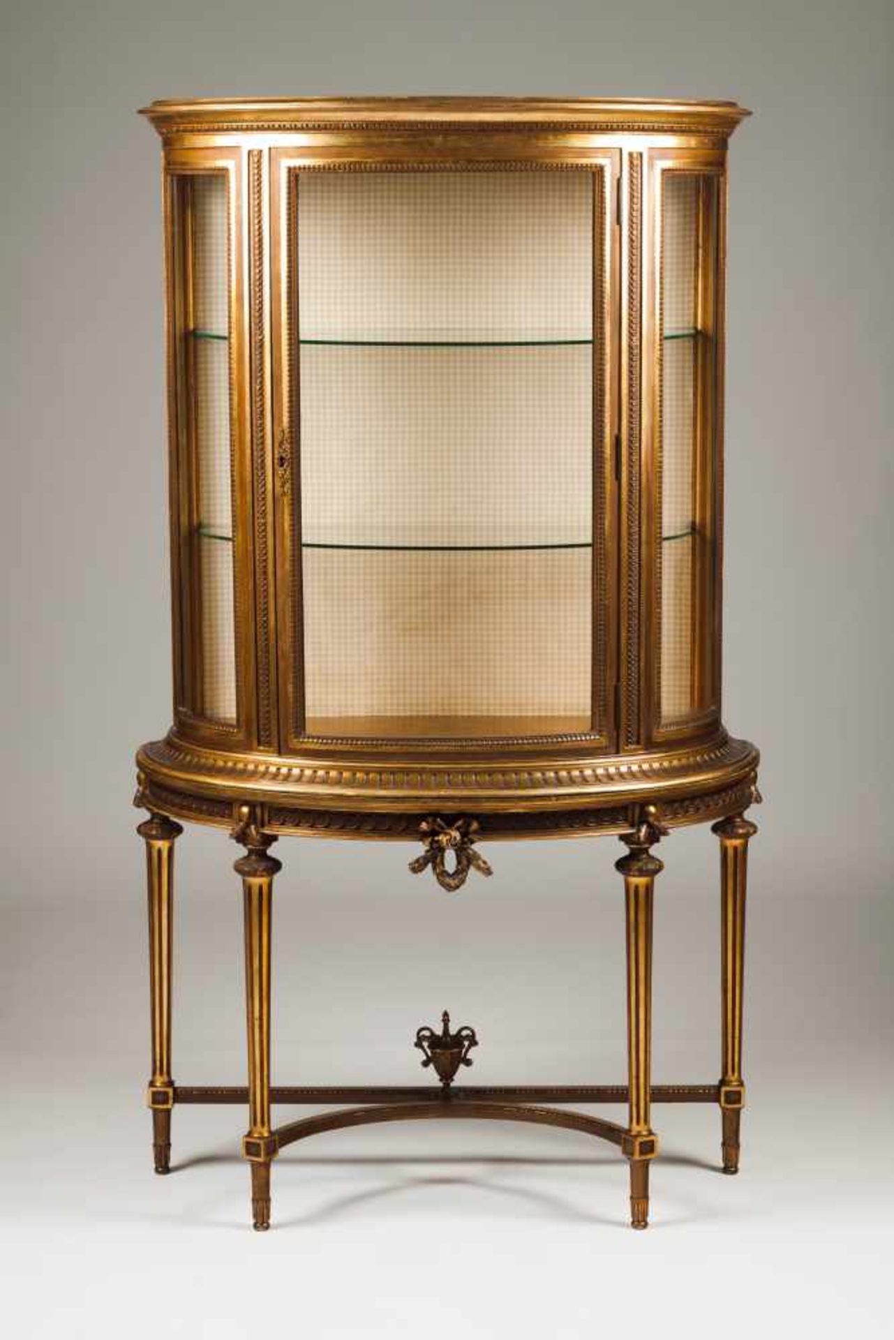 A Louis XVI style demi-lune showcaseGilt wood with carved decoration Interior with glass shelves20th