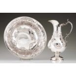 A ewer and basinPortuguese silver; dense foliage scroll inspired decoration. Volute handle and