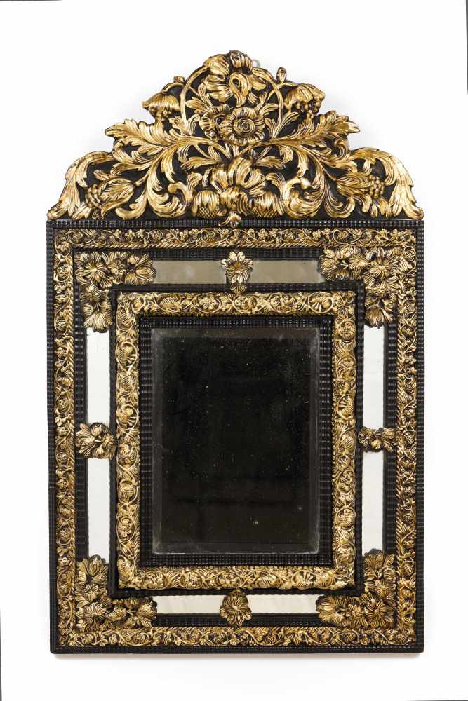 A mirrorWooden frameRaised gilt metal decoration of foliage scroll motifsScalloped upper