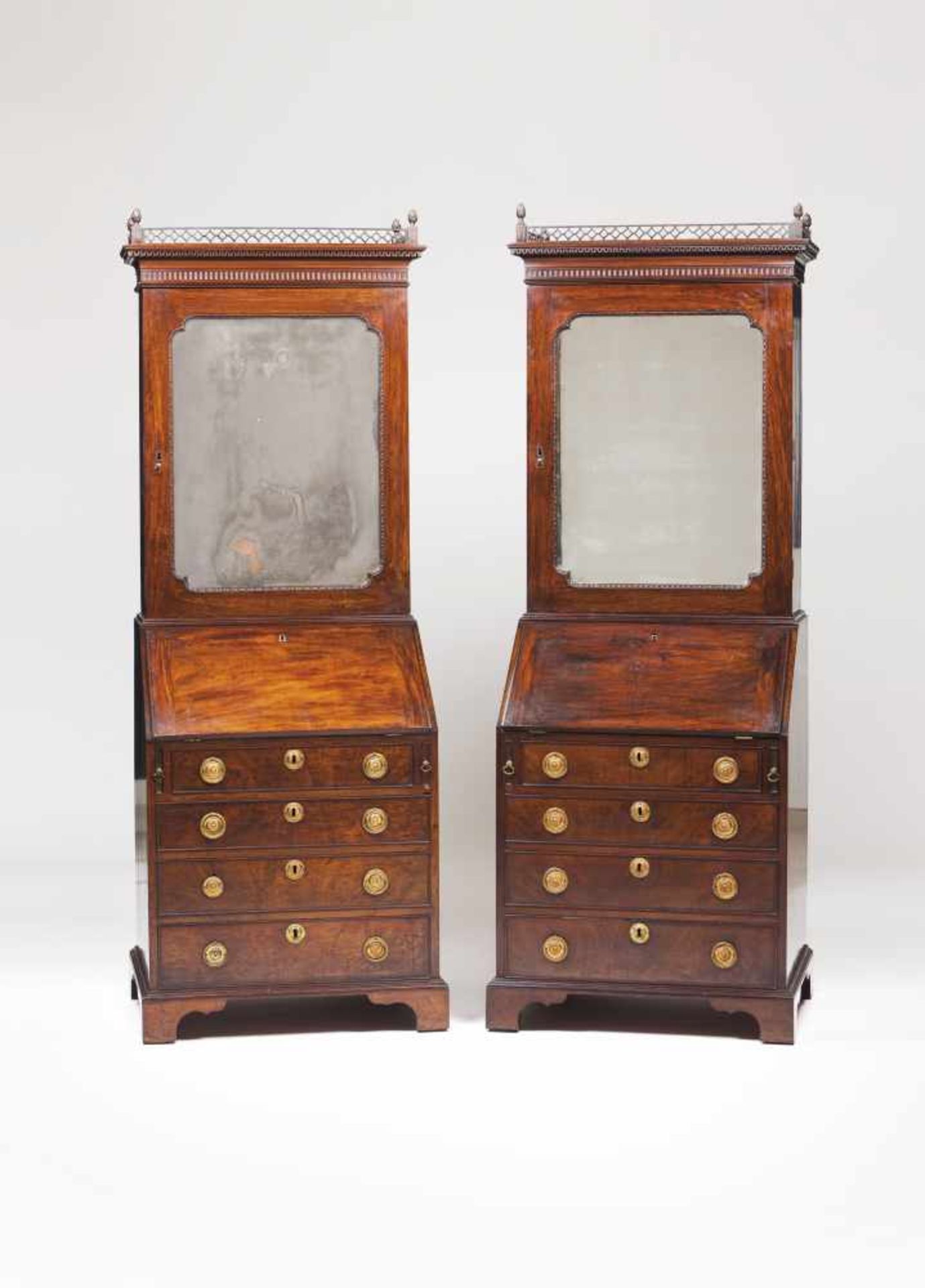 A pair of George III bureau bookcasesThe top with pierced and carved details and mirrored doors,