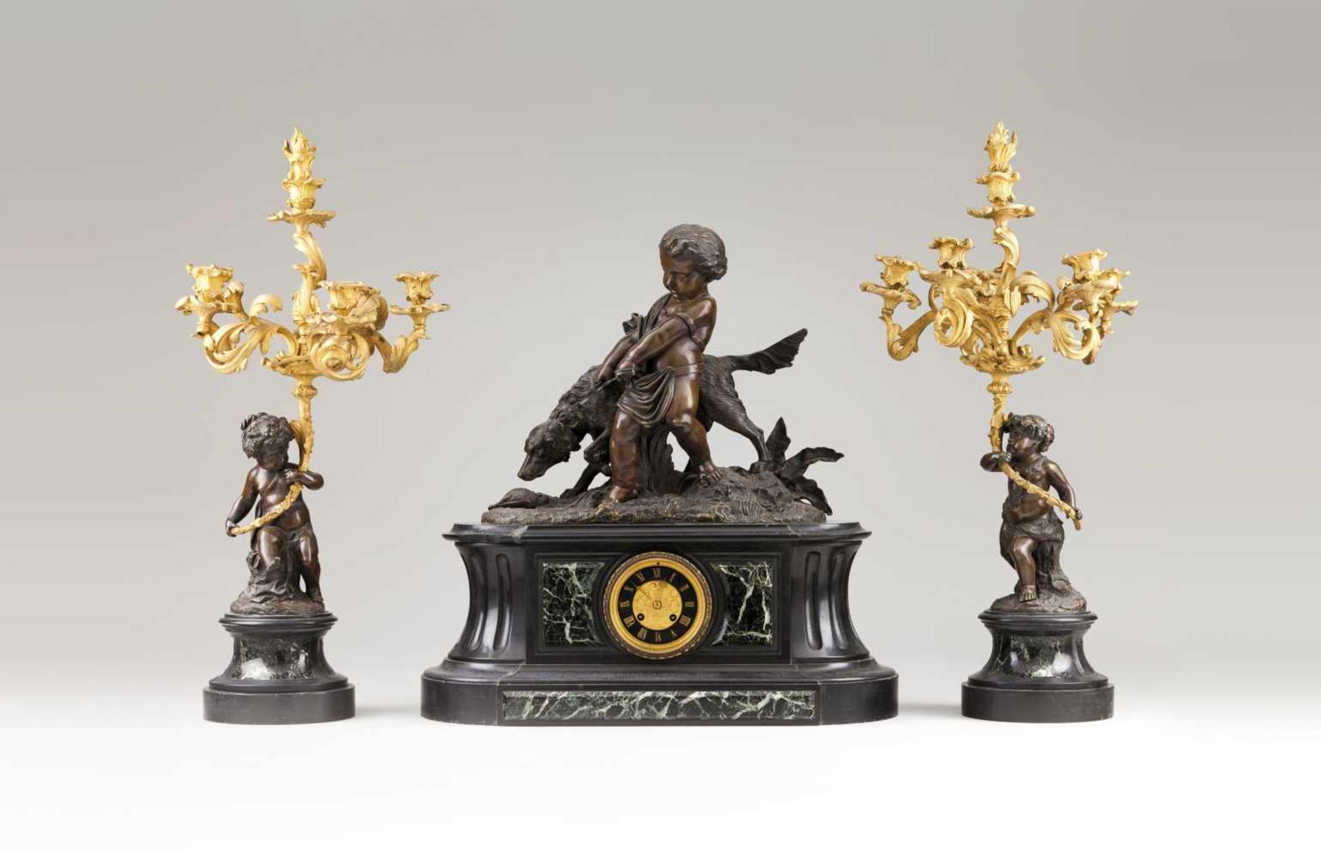 A Napoleon III garnitureGilt and patinated bronzeClock with boy and dog decorationTwo six branch