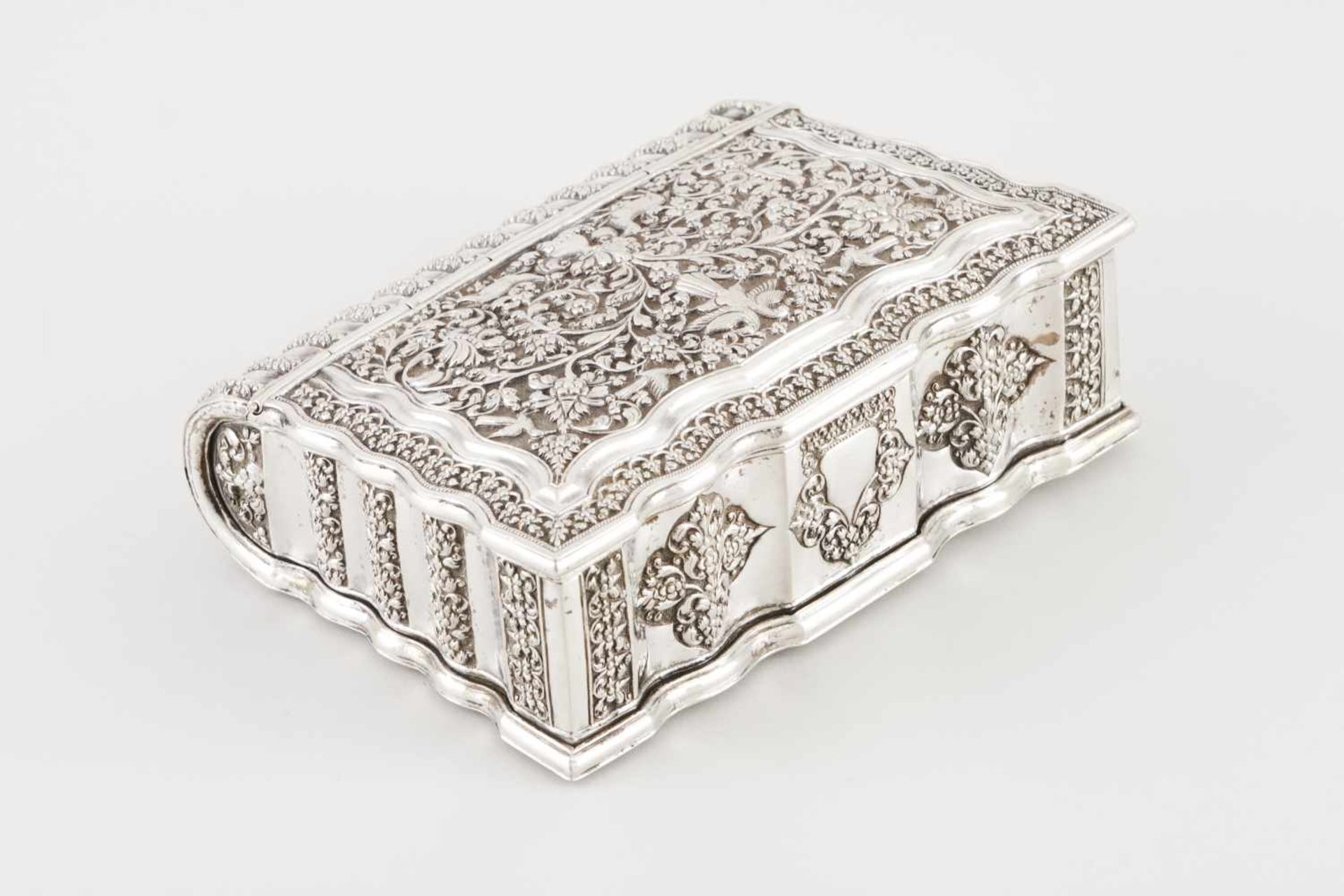 A boxIndian silverBook shaped with hinged cover profusely decorated with floral and foliage