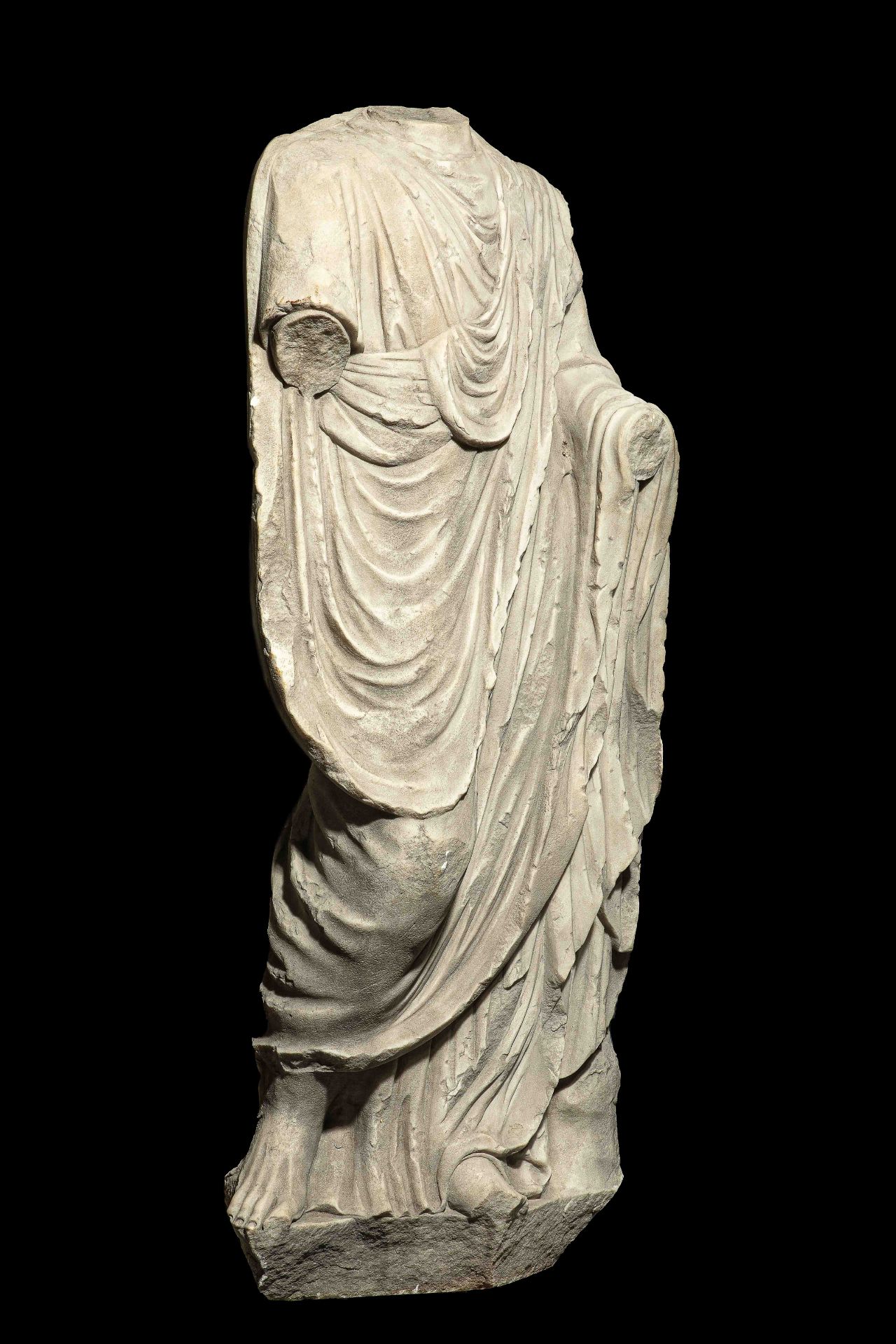 Statue acéphale masculine, vêtu d’une toge. Manques divers, resculpté au niveau [...]