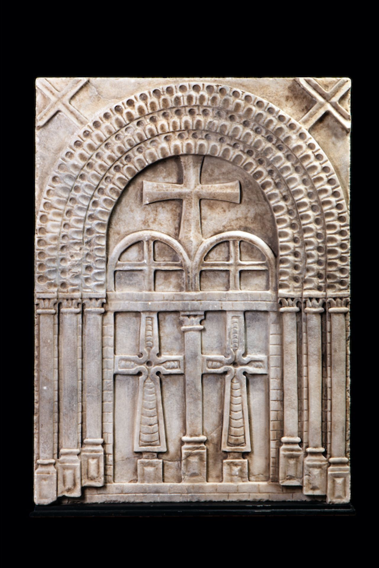 Relief en marbre orné de croix, et collonnes et arcades symbolisant une basilique. [...]