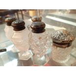 Four glass pepper shakers with silver tops and a possibly silver top mustard pot
