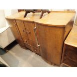 Light oak sideboard by Nathan with two side cupboards two lower drawers and a central drinks