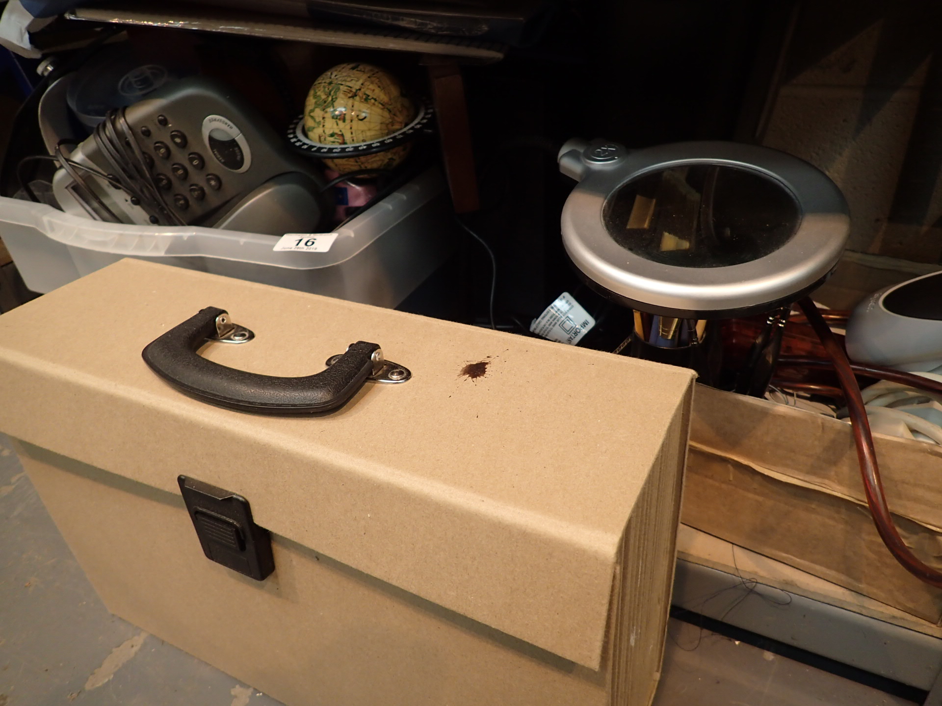 Shelf of office items including phone magnifier and table lamp