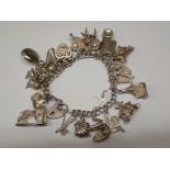 Silver charm bracelet with twenty two charms 65g