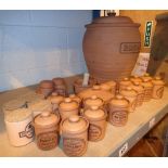Shelf of terracotta spice jars bread bin vinegar oil containers etc