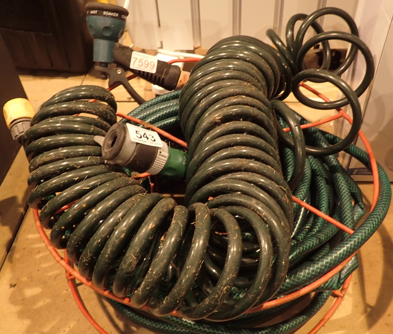 Two garden hose pipes one on reel with attachments