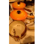 Four Le Creuset pans in flame orange