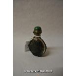 A Chinese glass snuff bottle, green cabochon stone to lid, carved with bats and leaves, 7cm.