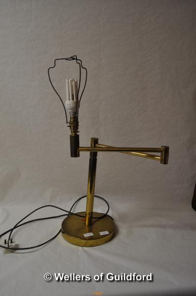 An adjustable brass table lamp on circular base.