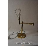 An adjustable brass table lamp on circular base.