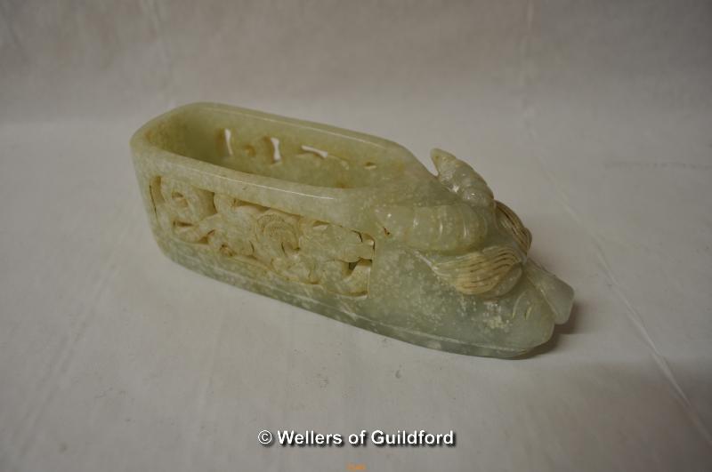 A Chinese pale green hardstone ornament designed as a slipper, 14.5cm long.